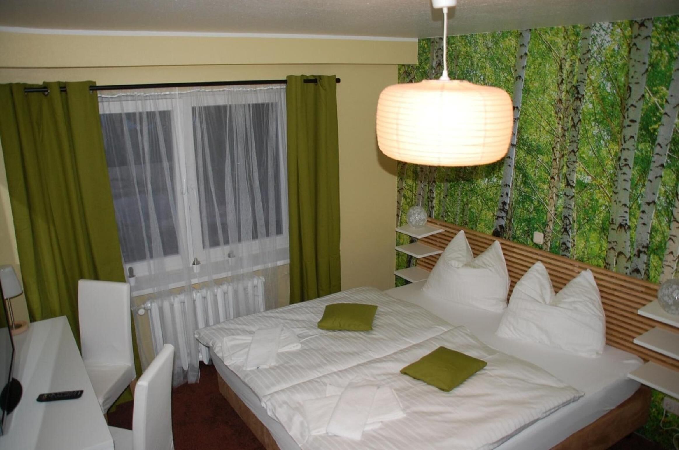 A hotel room with a bed, a desk, and a window with curtains.