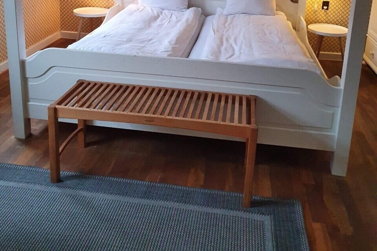 A bed with a canopy, two bedside tables, and a wooden bench.