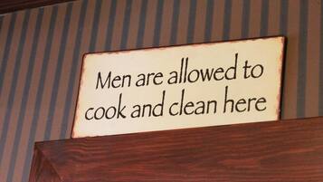 Un letrero con el texto: 'Aquí hombres pueden cocinar y limpiar'.