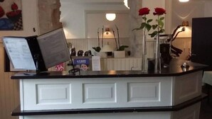 Una recepción con una decoración en blanco y negro, una lámpara colgante y un espejo encima.