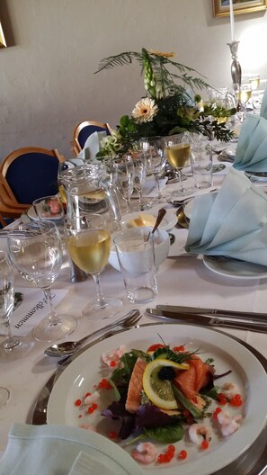 A table set for a meal with empty wine glasses, a plate of food, and a decorative centerpiece.