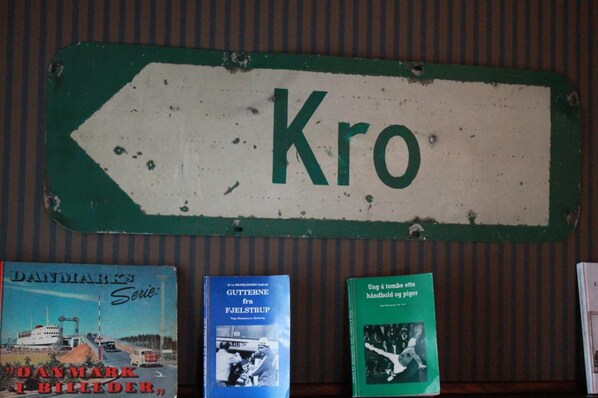 Una señal direccional verde con la palabra 'Kro' escrita, y tres libros debajo.