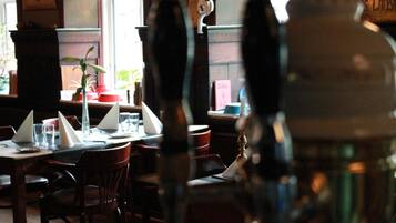 Un interno ristorante con tavoli e sedie in legno e un'ampia decorazione floreale.