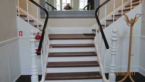 Una escalera con balaustres blancos y escalones de madera oscura.