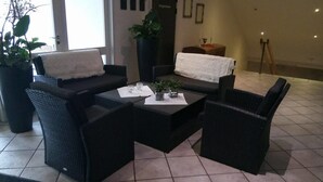 Una sala moderna con muebles de mimbre oscuro, una mesa de centro y plantas en macetas.