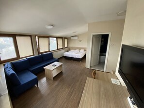 Une chambre d’hôtel moderne dotée d’un grand lit, d’un canapé, d’une télévision et d’un balcon avec de grandes fenêtres.