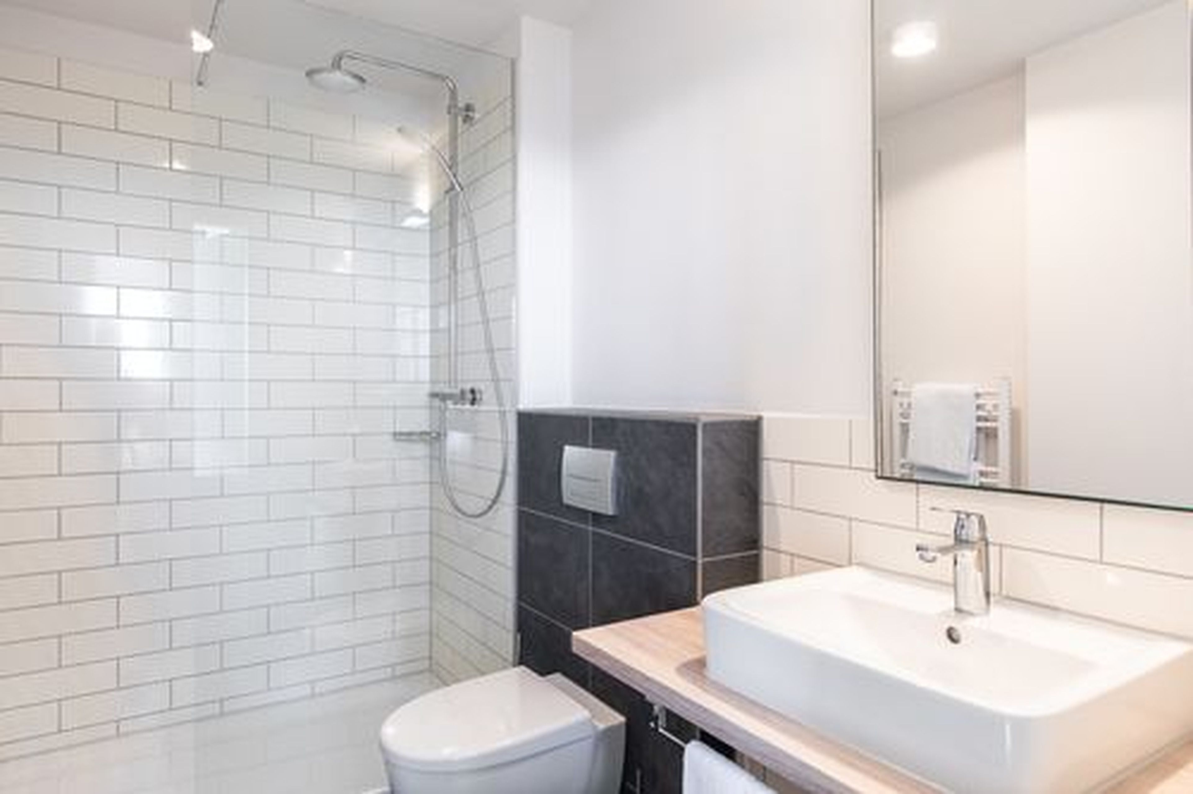 A modern bathroom with a glass shower enclosure, a white sink, and a toilet.