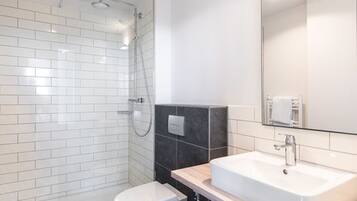 Ein modernes Badezimmer mit einer Duschkabine aus Glas, einem weißen Waschbecken und einer Toilette.