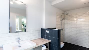 A modern bathroom with a white sink, dark shower enclosure, and a mirror.