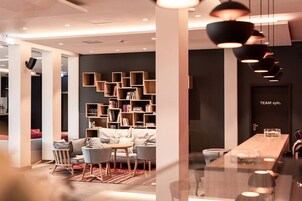 Ein modernes Interieur mit einer Sitzecke, einem langen Tisch und einem Bücherregal.