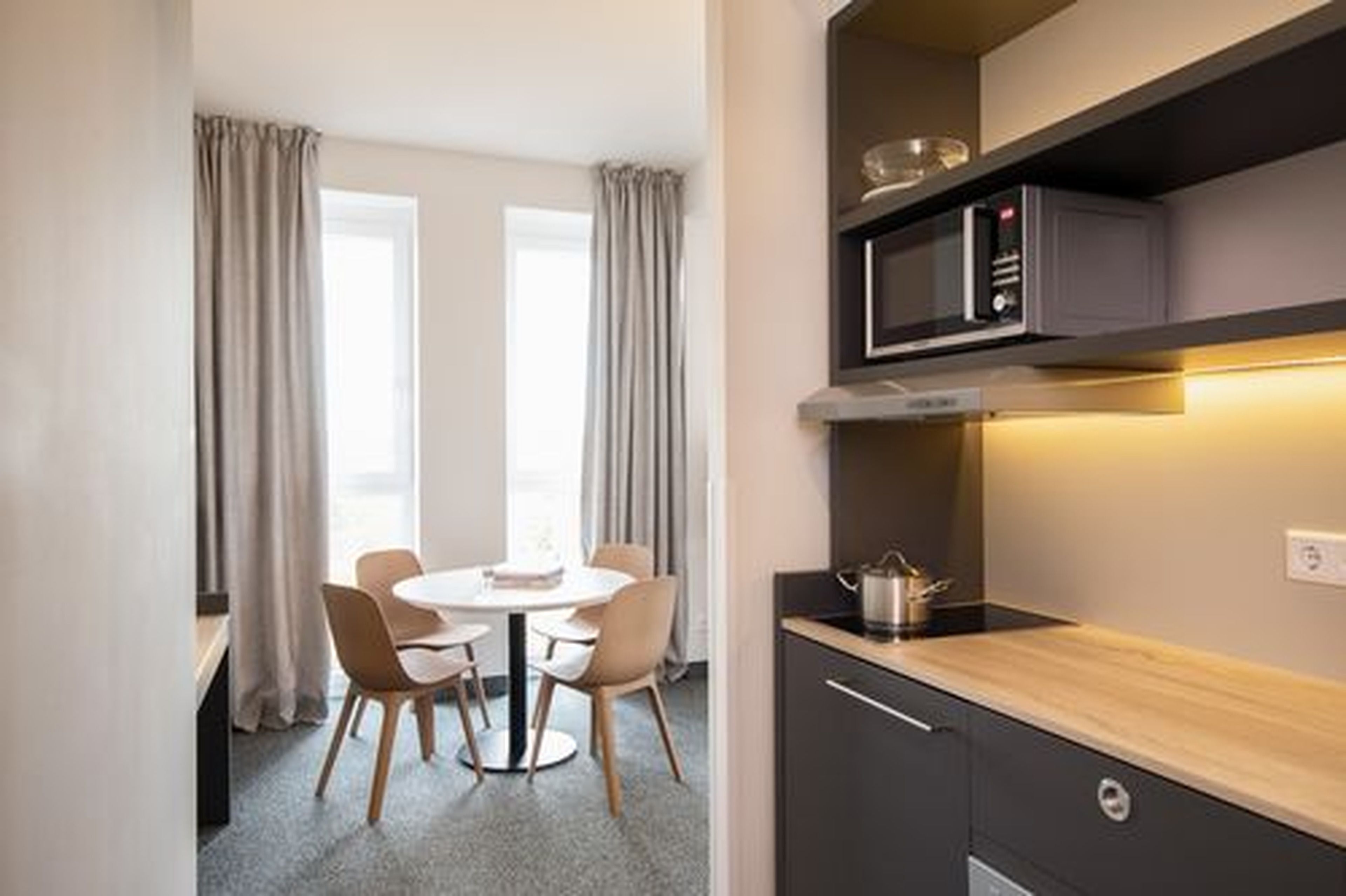 Une cuisine compacte équipée d’un four à micro-ondes, d’une petite cuisinière et d’un plan de travail en bois.