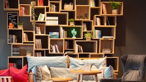 A cozy living room with a sofa, chairs, a coffee table, and a bookshelf filled with books and decorative items. - sylc. Apartmenthotel (Hamburg)