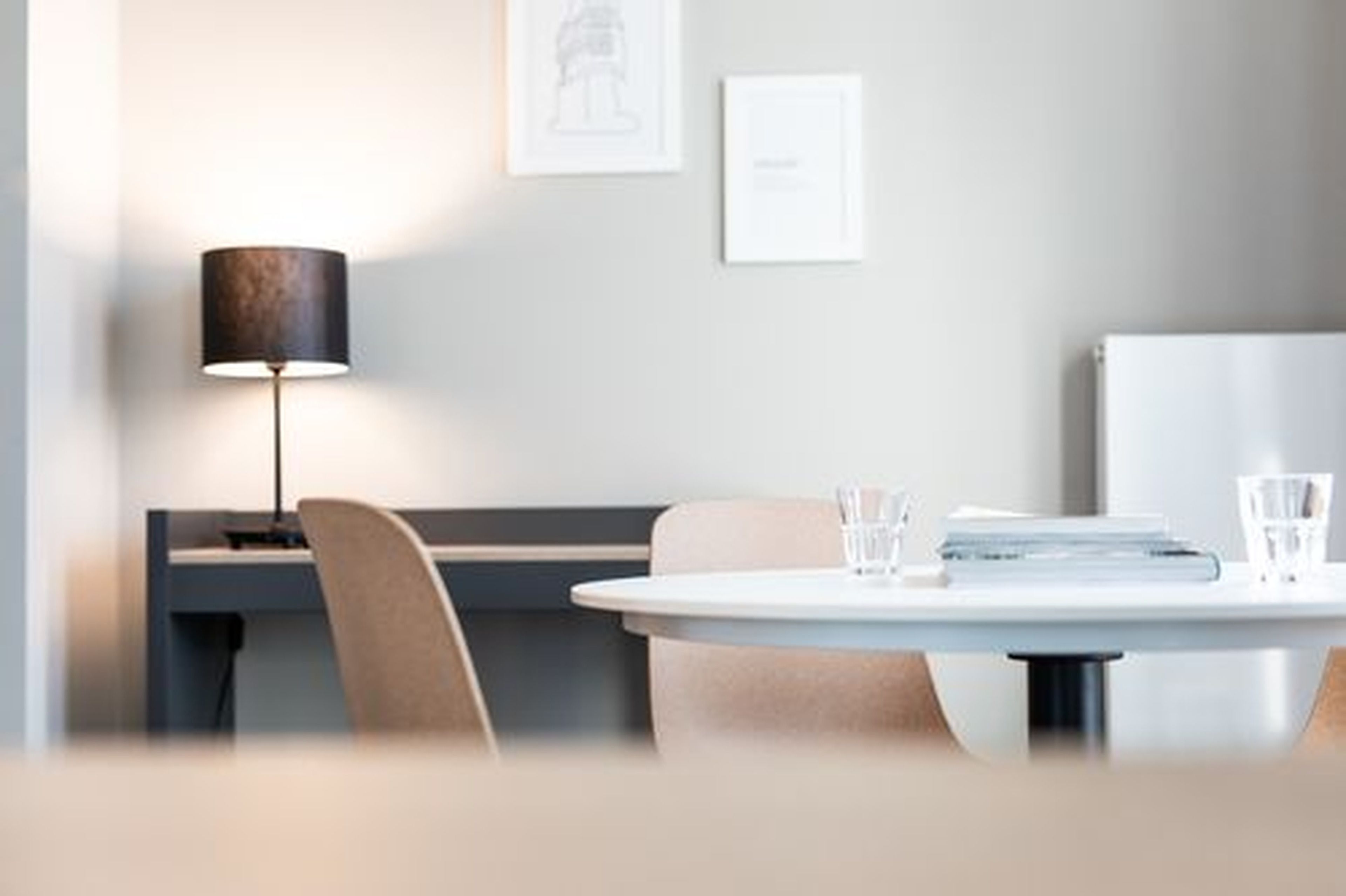 Quarto moderno com uma mesa redonda, uma escrivaninha e uma luminária.