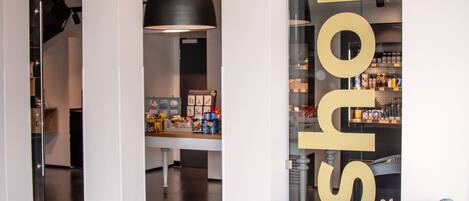 A modern interior with a large 'shop' sign, a counter with various products, and a hanging light fixture.