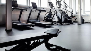 A gym with treadmills, stationary bikes, and a bench. - sylc. Apartmenthotel (Hamburg)