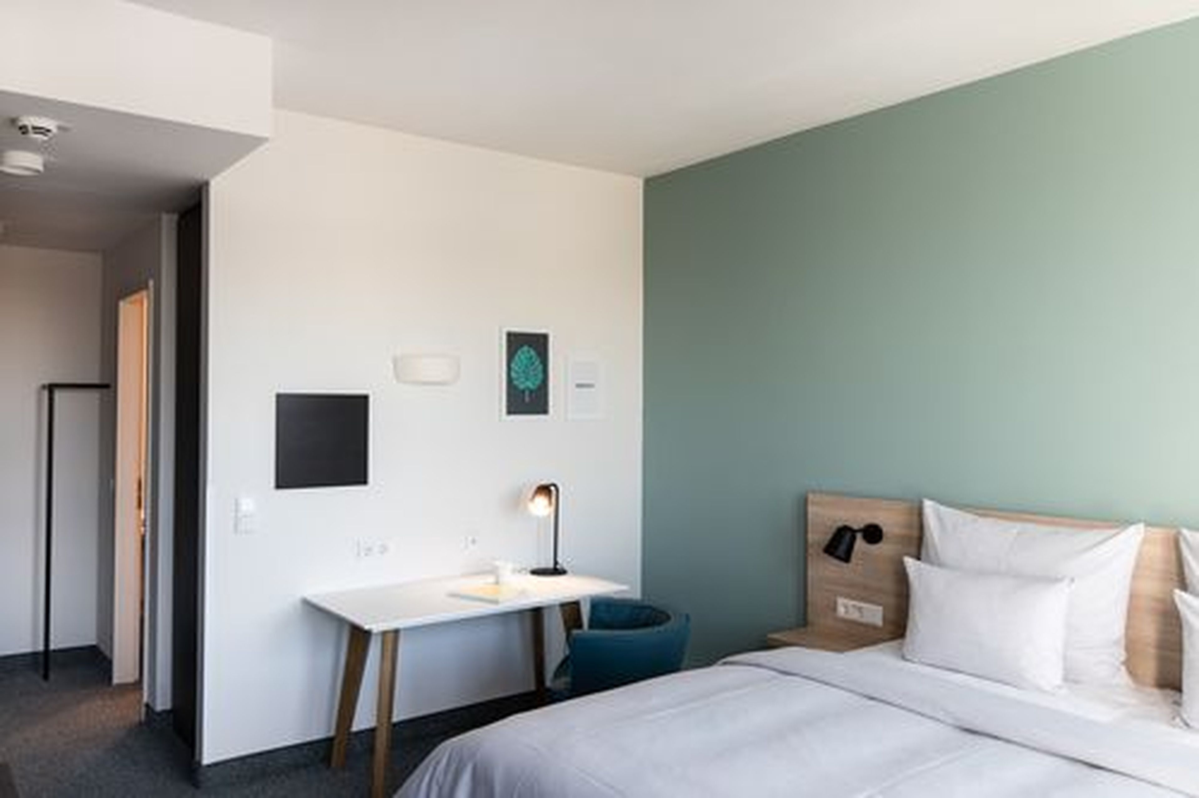 A hotel room with a bed, a desk, and a chair.