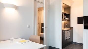 A modern kitchen with a built-in oven, a sink, and a countertop. There is a white table with a glass and a book.