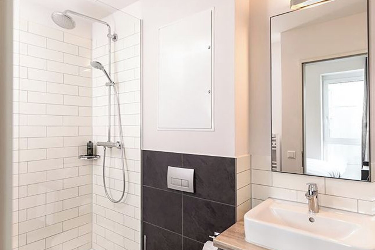 A modern bathroom with a shower, a sink, and a mirror.