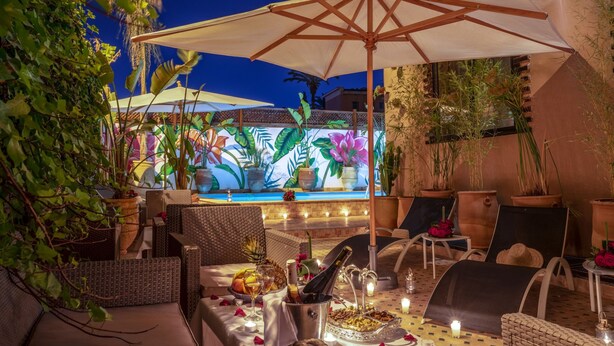 An outdoor dining area with wicker furniture, a pool, and a mural in the background. - Majorelle City Center Boutique Hôtel (Marrakech)