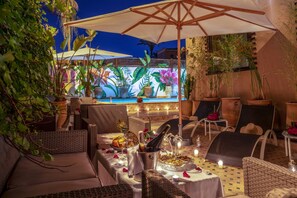 An outdoor dining area with wicker furniture, a pool, and a mural in the background. - Majorelle City Center Boutique Hôtel (Marrakech)