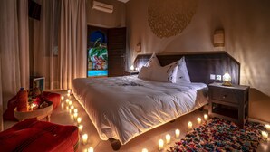 A bedroom with a large bed, bedside tables, a nightstand, and a wall mural. - Majorelle City Center Boutique Hôtel (Marrakech)