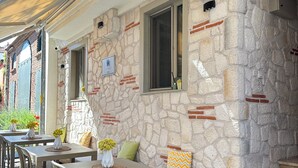A stone exterior with a covered outdoor seating area, a doormat, and a small window. - Evren Butik Otel (Bozcaada)