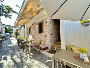 An outdoor café with stone walls, wooden tables, and chairs. - Evren Butik Otel (Bozcaada)