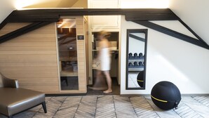 A room with a herringbone-patterned floor, a black exercise ball, and a mirrored wall. - Hotel Arok (Strasbourg)