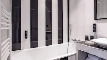 A modern bathroom with a large bathtub, a separate shower area, and a vanity with a mirror.