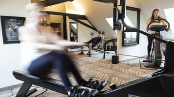 Ein Fitnessraum mit Trainingsgeräten, einem Spiegel und einem Poster an der Wand.