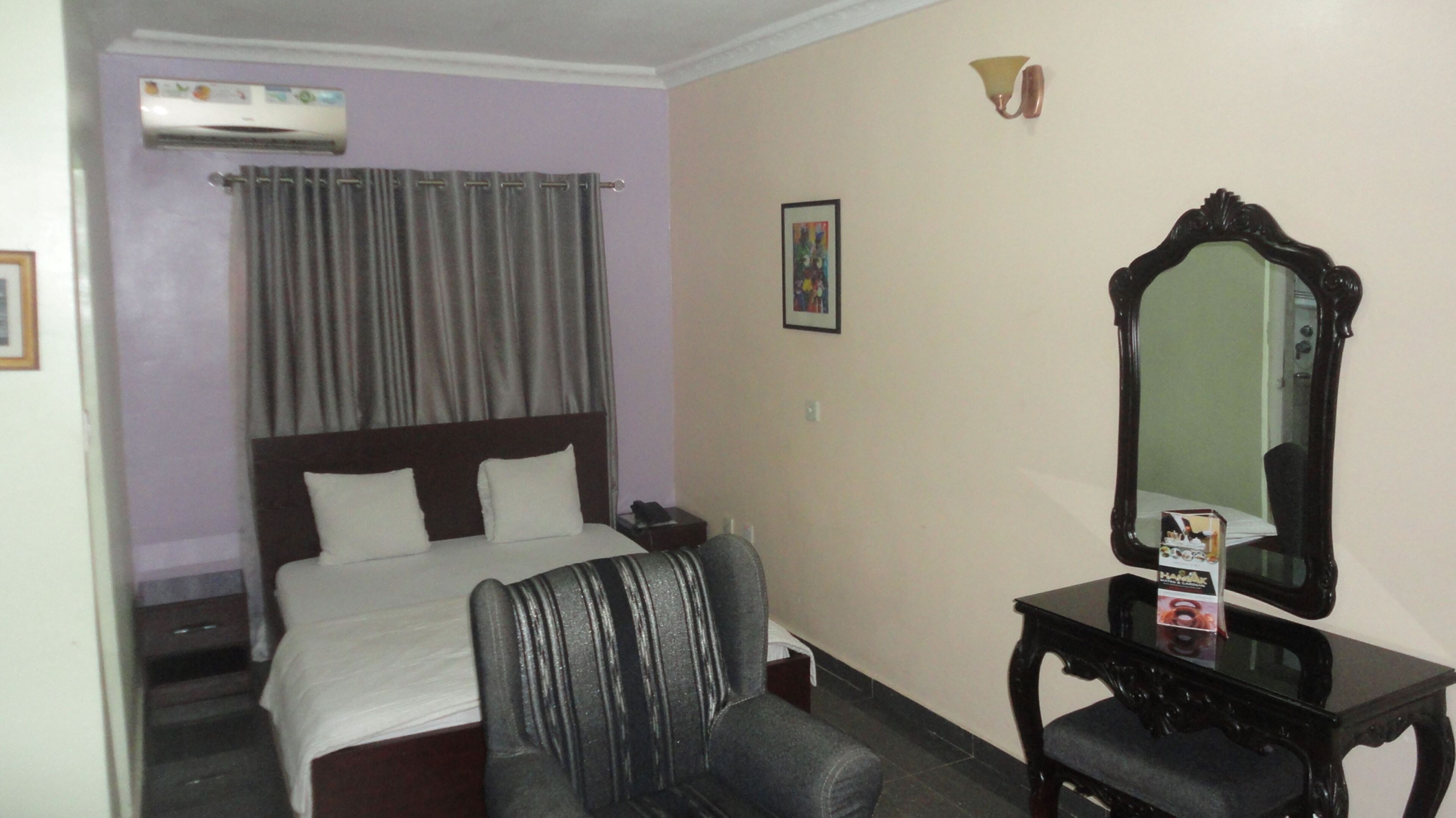 Habitación de hotel con cama, escritorio con espejo y una silla.