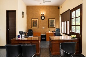 A conference room with two desks, chairs, a clock, and framed pictures on the wall. - Enkay Residency V Block-Cyber City (Gurugram)