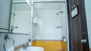 A bathroom with a white sink, a glass shower enclosure, and a wooden door. - Enkay Residency V Block-Cyber City (Gurugram)