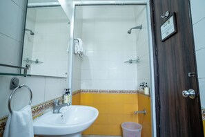 Un baño con un lavabo blanco, cabina de ducha con paredes de vidrio y una puerta de madera.