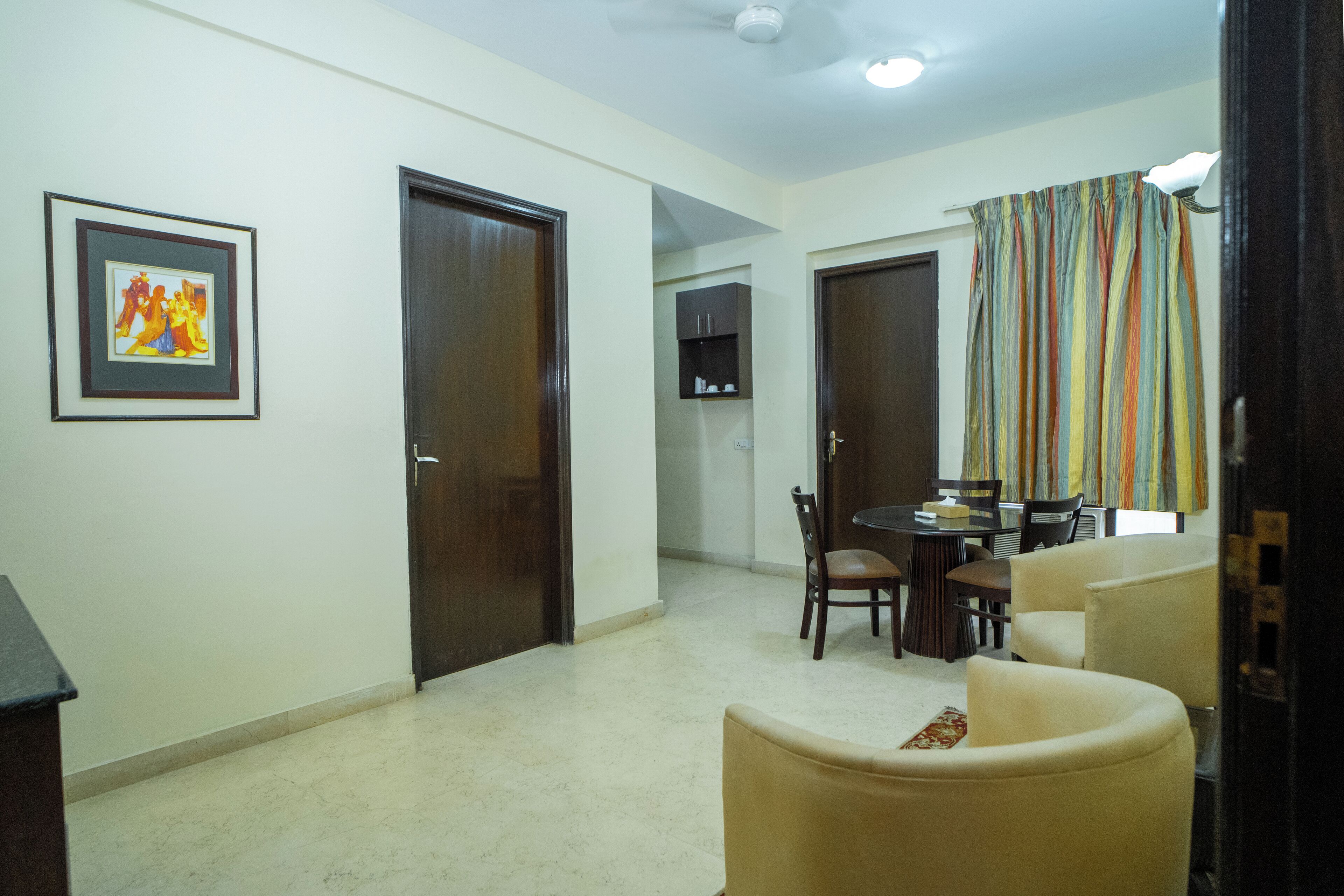 Uma sala de estar com área de jantar, com um sofá, cadeiras, uma mesa e um quadro na parede.