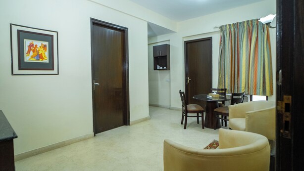 A living room with a dining area, featuring a sofa, chairs, a table, and a framed picture on the wall. - Enkay Residency V Block-Cyber City (Gurugram)