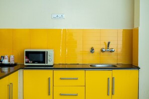 Una cocina con gabinetes amarillos, un microondas, un lavabo y un enchufe en la pared.
