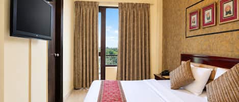 A hotel room with a bed, a TV, a nightstand, and a window with curtains.