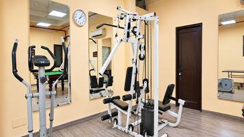 Un gimnasio con equipo de ejercicio, un reloj y una puerta.