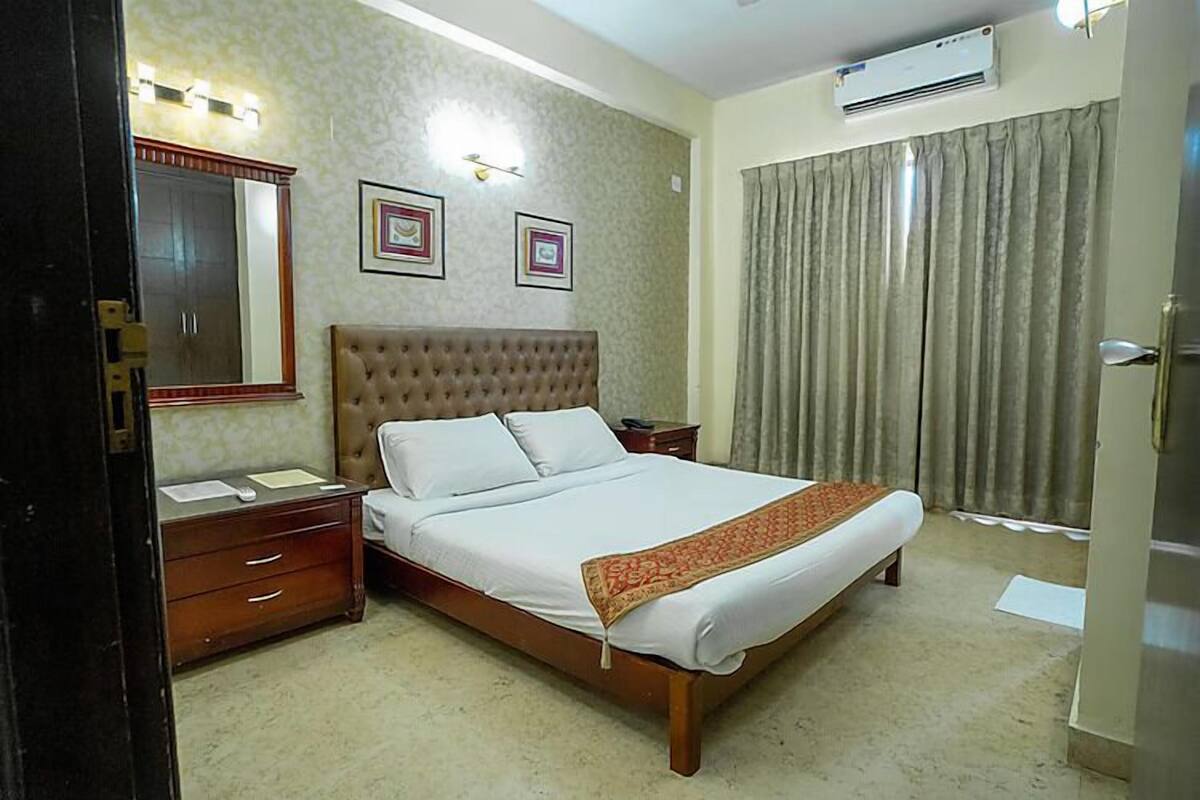 Ein Hotelzimmer mit einem großen Bett, einem Nachttisch, einem Spiegel und einem Kleiderschrank.
