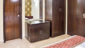 A room with a wooden wardrobe, a mirror, and a red patterned rug. - Enkay Residency V Block-Cyber City (Gurugram)
