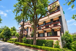 Un edificio de varios pisos con balcones, rodeado de vegetación y árboles.