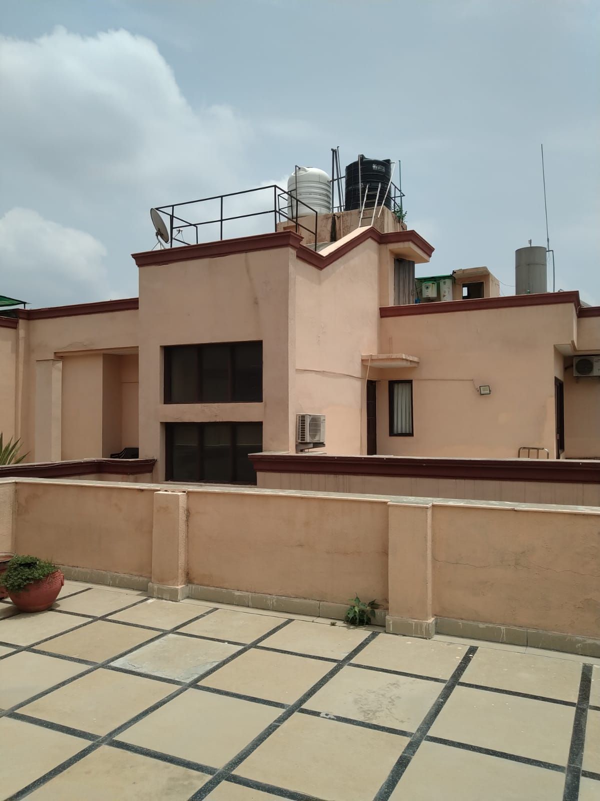 Edifício residencial com telhado plano, antena parabólica e aparelhos de ar condicionado.