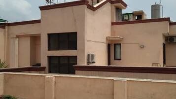 Edifício residencial com telhado plano, antena parabólica e aparelhos de ar condicionado.