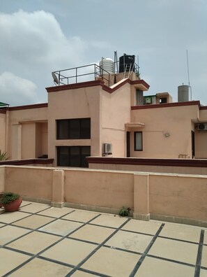 Un edificio residencial con techo plano, antena parabólica y unidades de aire acondicionado.