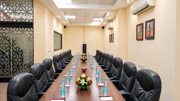 A conference room with a long table, black leather chairs, water bottles, name cards, and floral centerpieces.