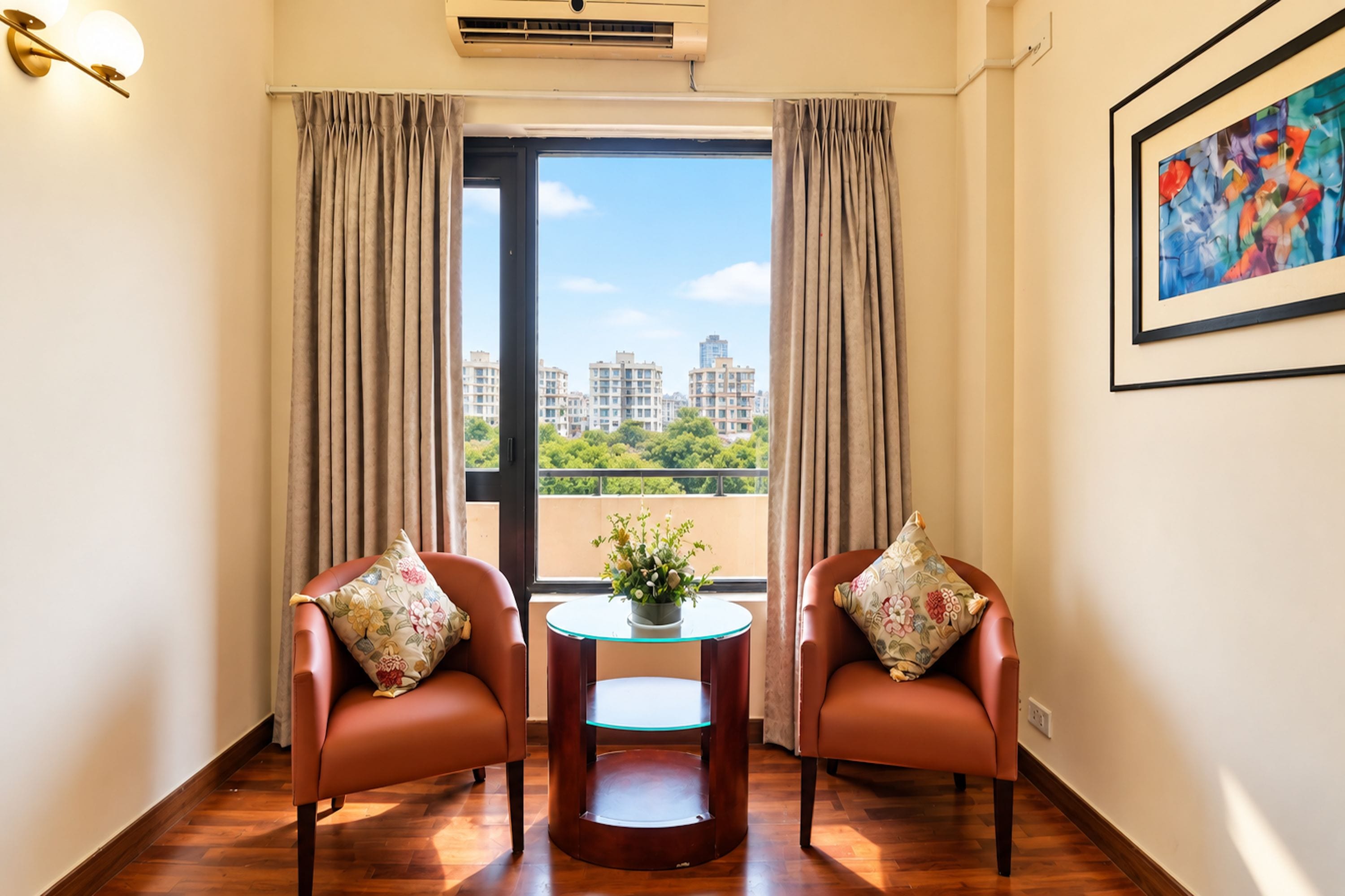 A room with two leather chairs, a small table with a vase, a window with curtains, and a painting on the wall.