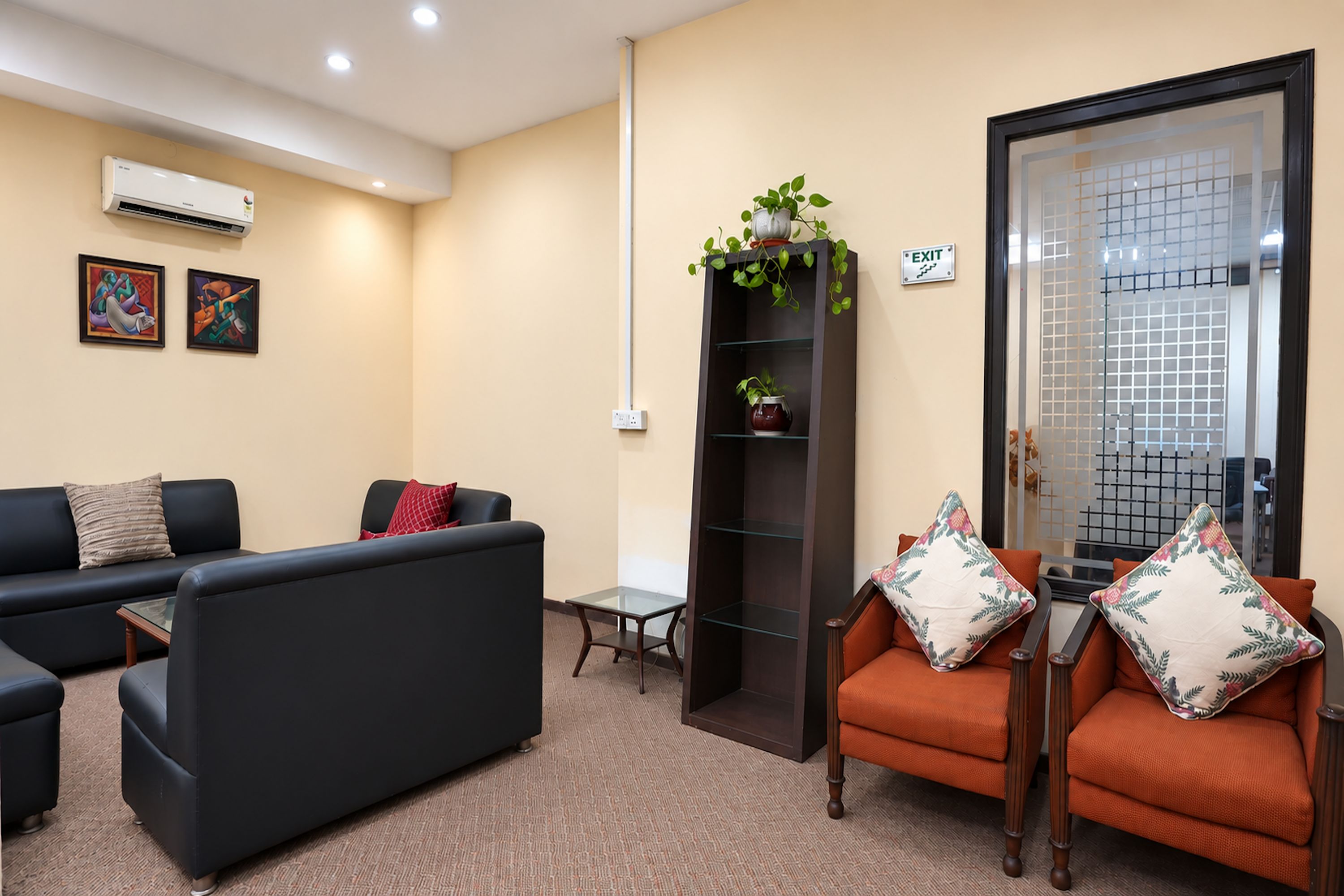 A modern waiting area with a sofa, chairs, a small table, and a decorative plant.