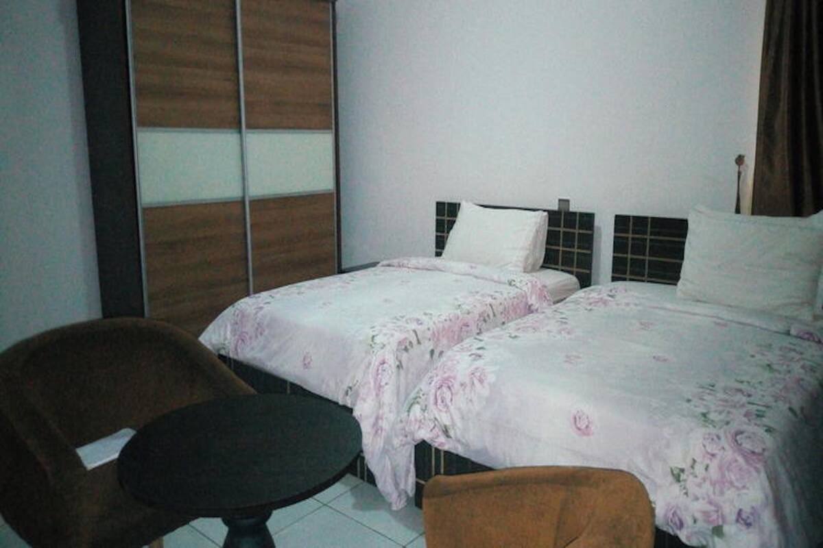 A hotel room with two beds, a chair, and a small table.