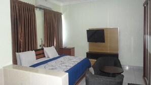 Una habitación de hotel con una cama, un televisor, una mesita y una silla.